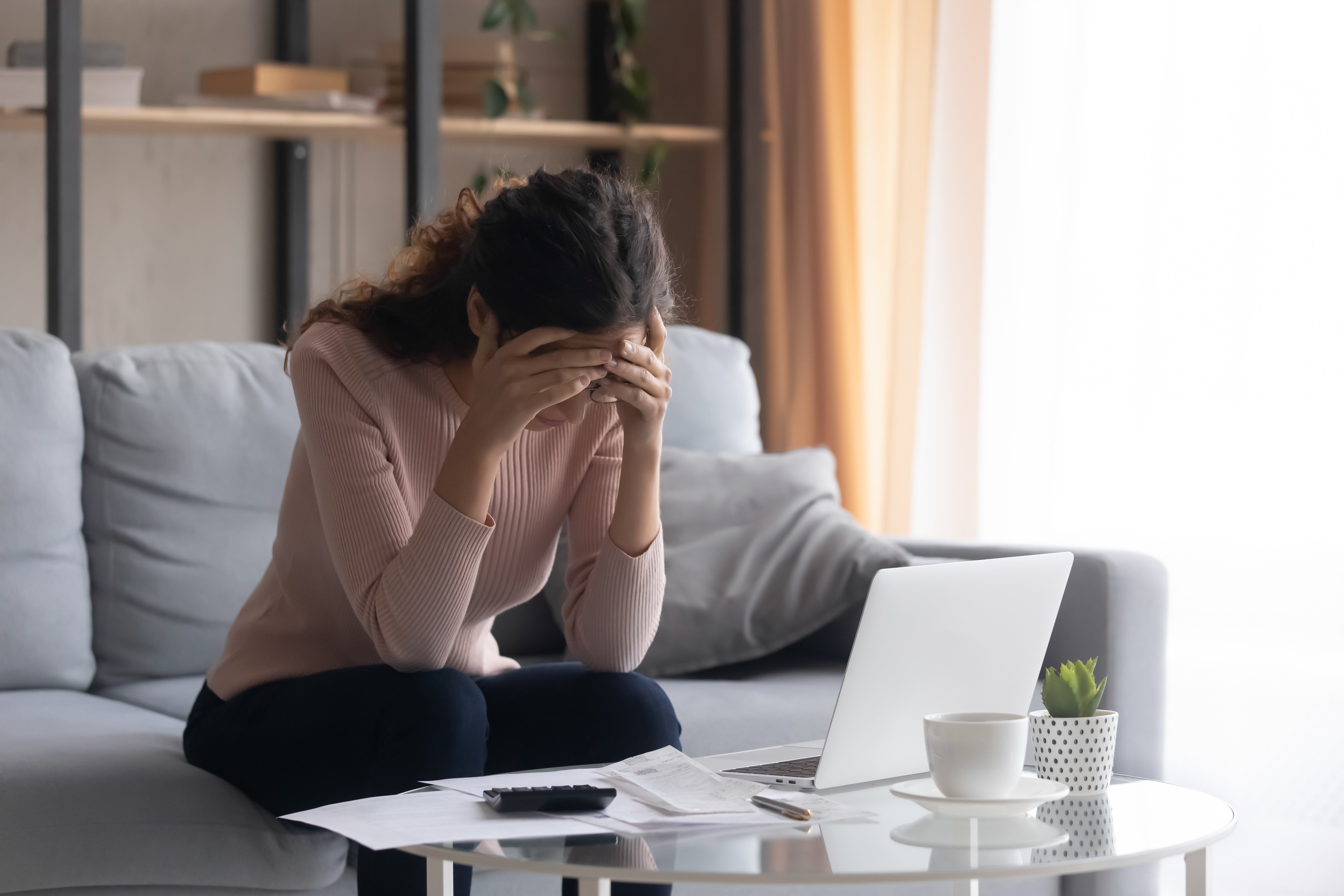 Žena hledá ve stresu s kalkulačkou a notebookem před ní | Zdroj: Shutterstock