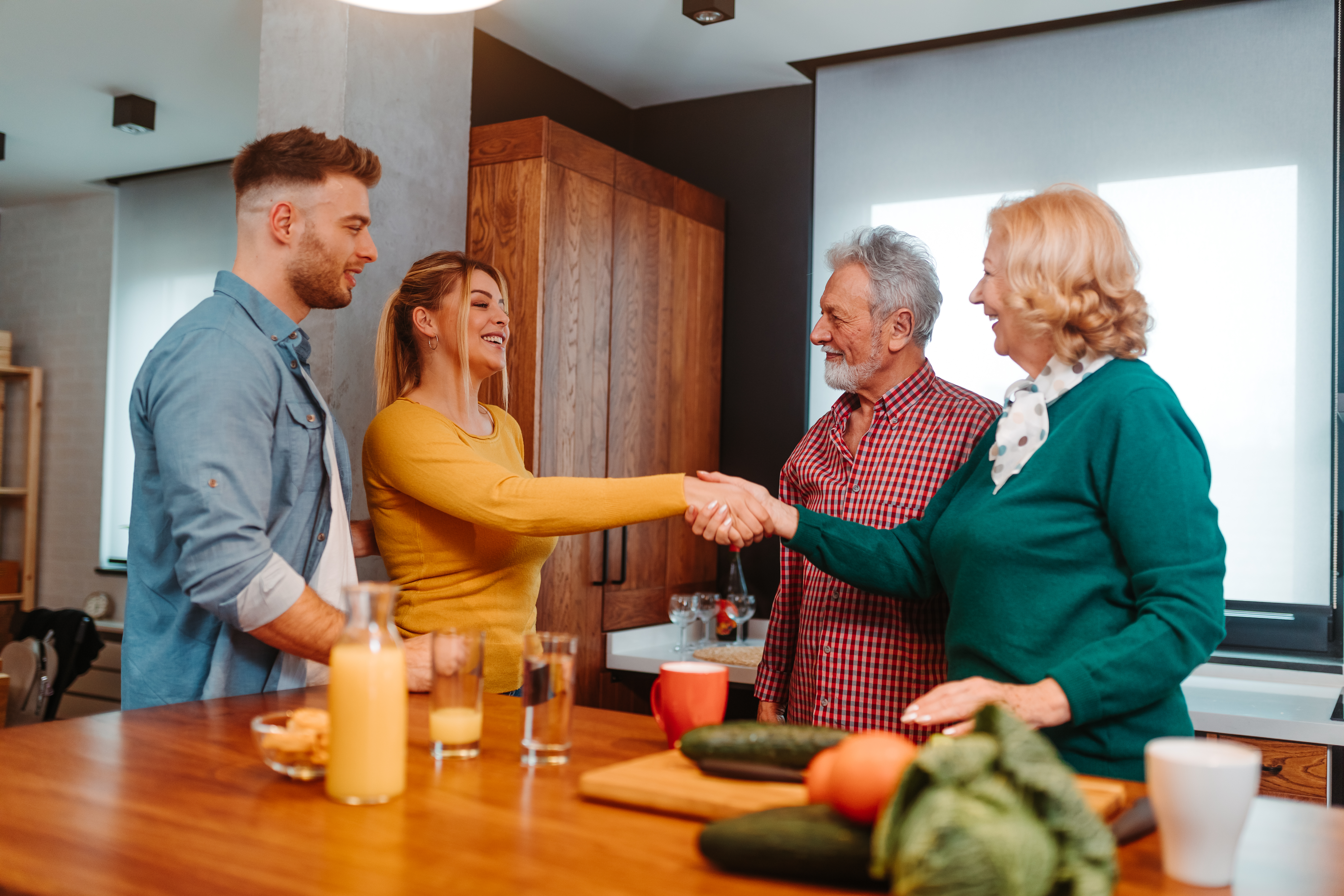 Mladá žena si potřese rukou s mámou svého partnera, když se on a jeho táta dívají na | Zdroj: Shutterstock