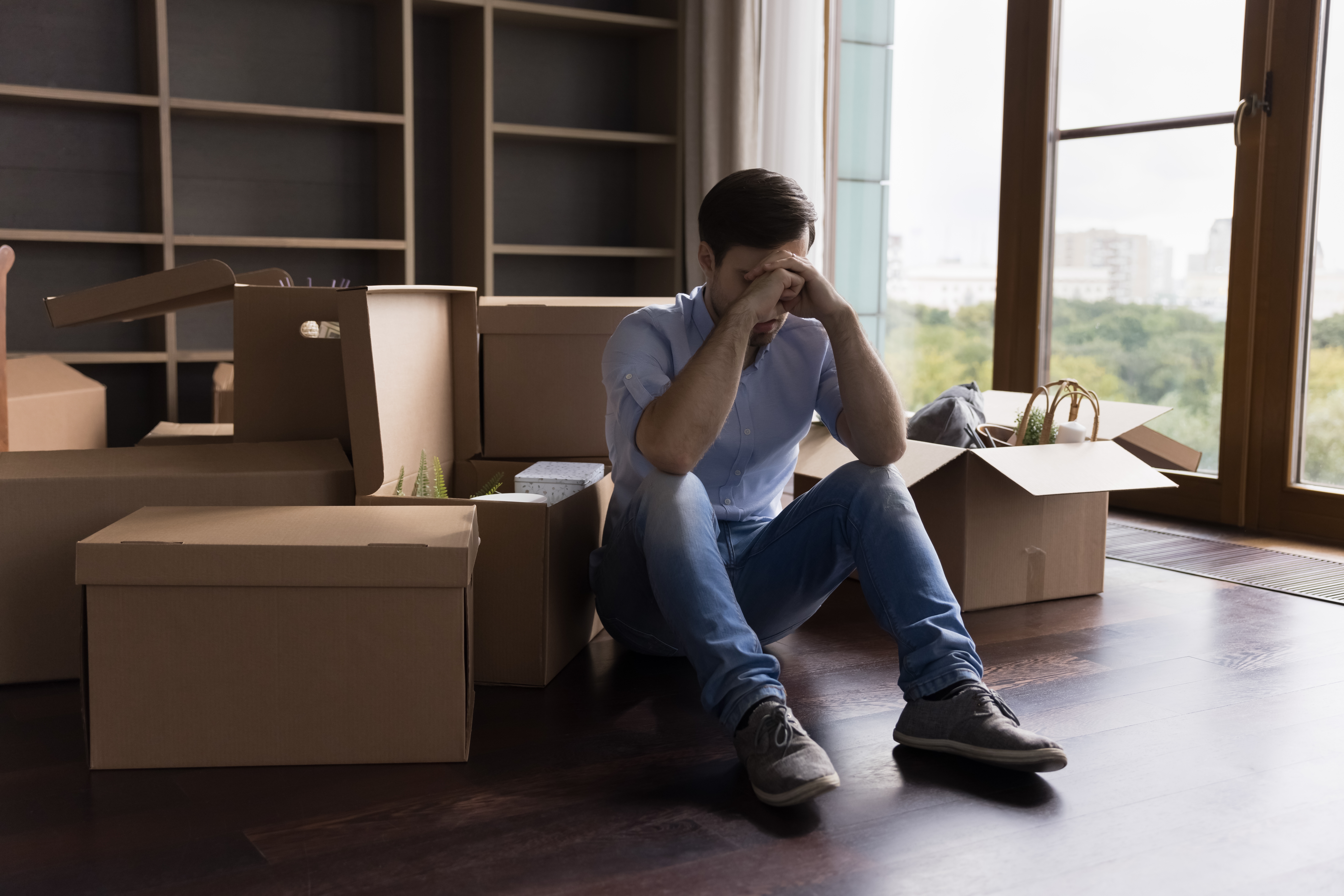 Mladý muž sedící na podlaze obklopený stěhovacími krabicemi | Zdroje: Shutterstock